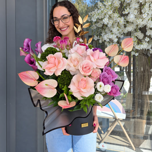 Aurore - Peach Roses & Purple Callas, held in front of the Lelili shop